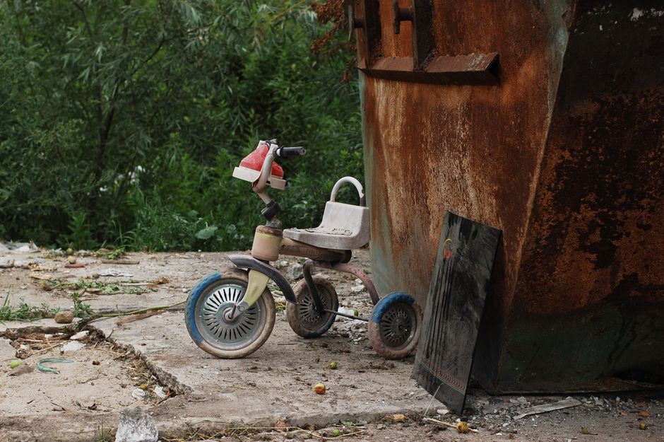 An outdoor recycling area featuring a large white shipping container with a blue sign that reads 'RECYCLING ONLY' positioned above a pile of discarded cardboard boxes and paper packaging materials. Th