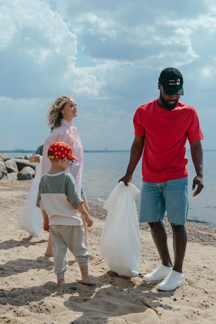 A person wearing a checkered shirt in shades of yellow, blue, and gray, along with green gloves, is holding open a large black plastic rubbish bag in an outdoor setting. The bag appears to be made of 